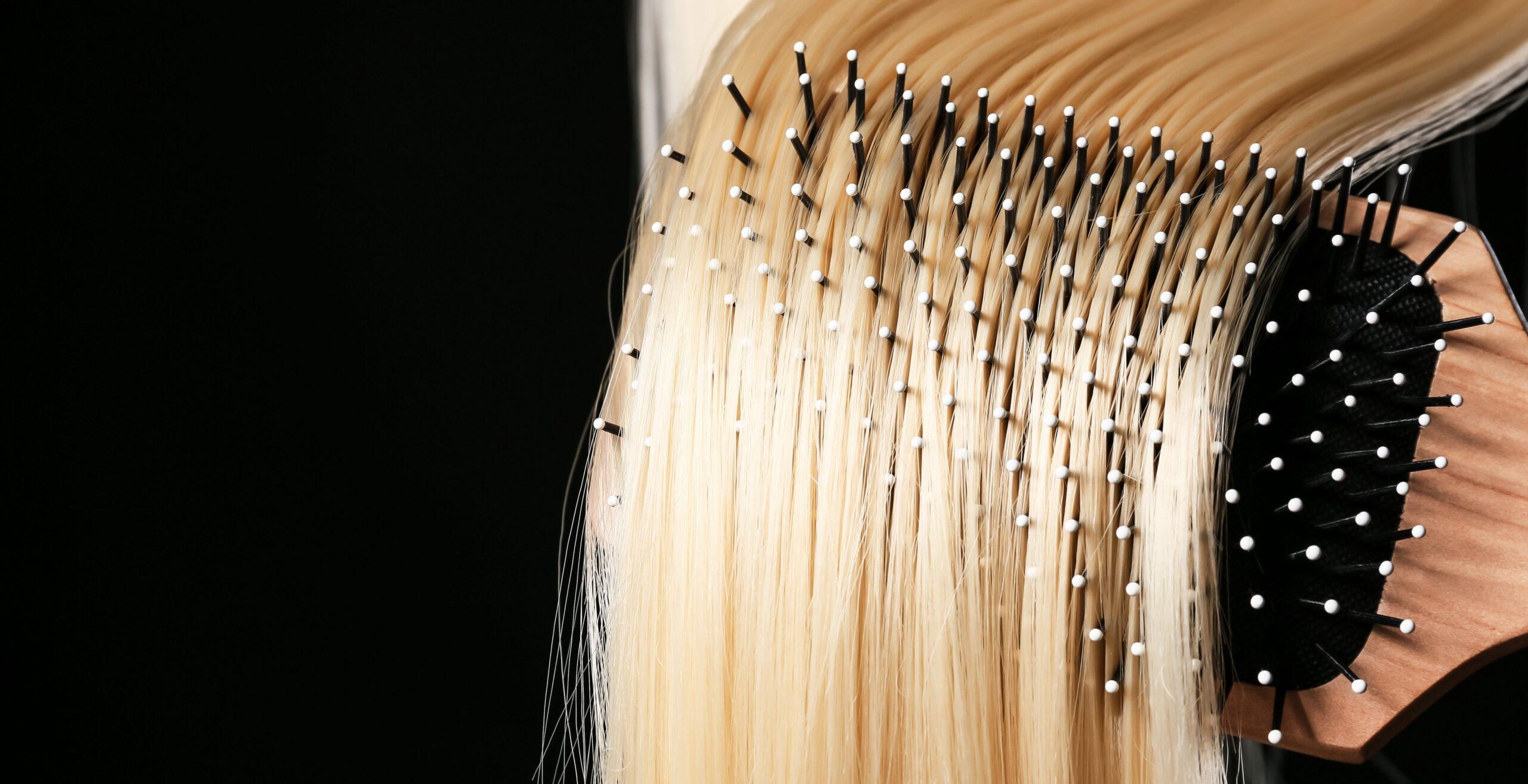 Bürsten von langen blonden Haaren auf dunklem Hintergrund