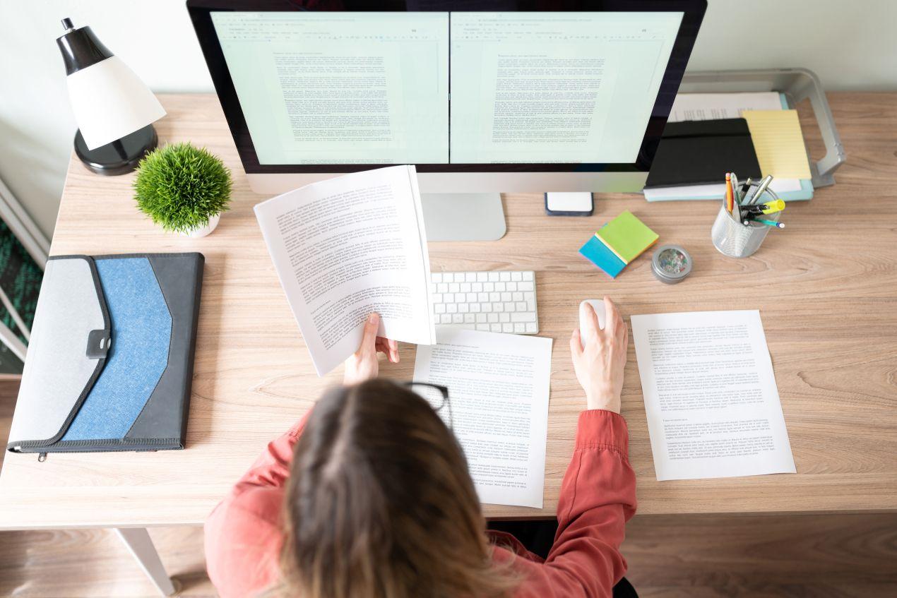 Ghostwriter strukturiert Dokumente an modernem Schreibtisch mit zwei Bildschirmen zur professionellen Texterstellung