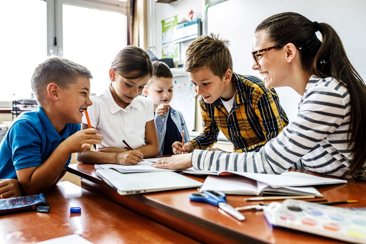 Lehrerin arbeitet mit Schuelern an einem Tisch – kollaborativer Unterricht in der privatschule berlin mit individueller Foerderung
