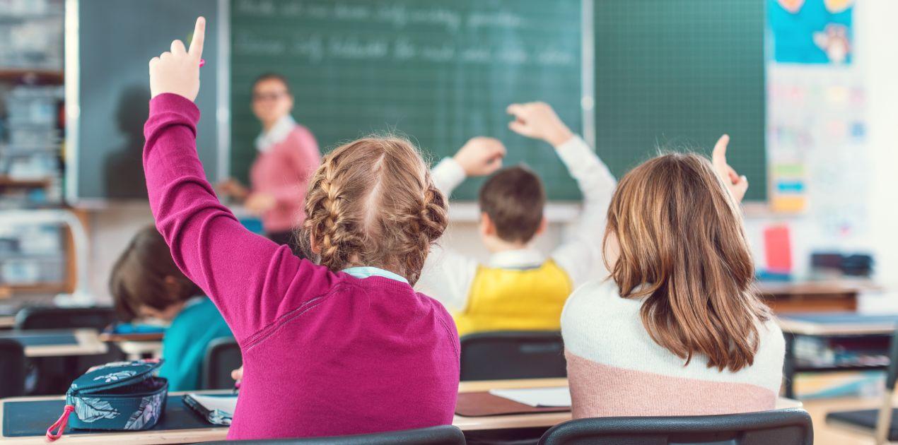 Kinder heben im Klassenzimmer die Hand – engagiertes Lernen in der privatschule berlin mit interaktiver Didaktik